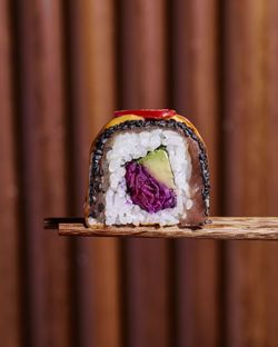 Sushi à emporter avec riz, avocat, poisson et légumes, présenté sur baguettes en bois. Restaurant de sushis.