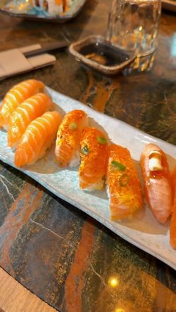 Assortiment de sushi au saumon présenté sur une assiette blanche dans un restaurant japonais.