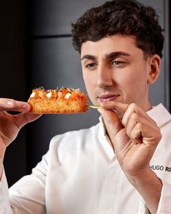 Un chef tenant un sushi croustillant garni de saumon et fromage dans un restaurant japonais à emporter.