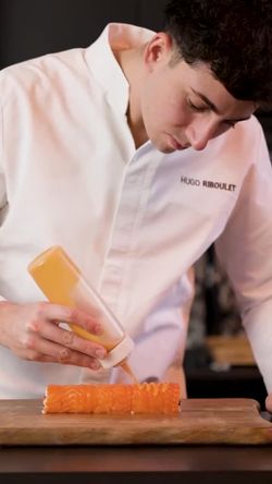 Préparation de sushi avec sauce versée sur un rouleau de saumon dans un restaurant japonais