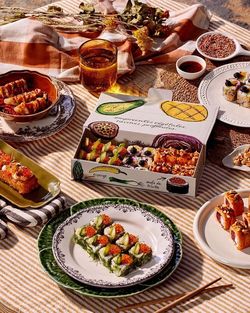 Livraison sushi avec plateau de sushi variés et plusieurs accompagnements dans un cadre éclairé naturellement.