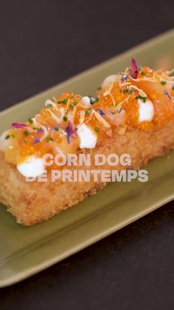 Corn dog de printemps présenté sur une assiette verte avec garniture colorée et décoration florale.