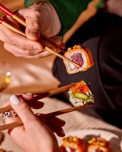 Deux personnes tiennent des sushis avec des baguettes dans un restaurant japonais avec sushi à emporter.