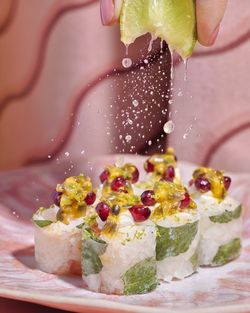 Sushis à emporter garnis de fruits de la passion et grenade, avec un citron pressé pour ajouter de la fraîcheur.