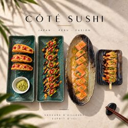 Assortiment de sushis et brochettes présentés sur quatre plats rectangulaires aux couleurs naturelles, décor minimaliste.