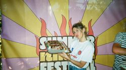 Jeune femme tenant un plateau de sushis devant une bannière colorée au Côté Sushi Versailles.