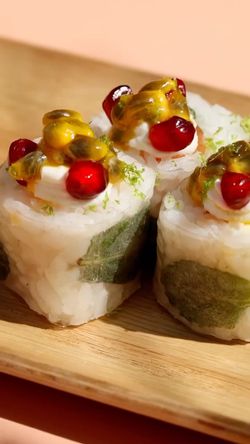 Trois sushis garnis de fruits exotiques et d'herbes, servis sur un plateau en bois au restaurant japonais Coté Sushi Tours.