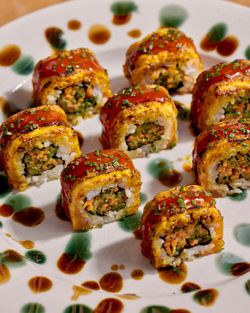 Sushis colorés garnis de légumes et sauce, servis sur une assiette avec décorations en sauce.