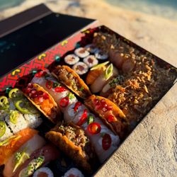 Assortiment coloré de sushi à emporter dans une boîte avec divers garnitures et makis, présenté au soleil.