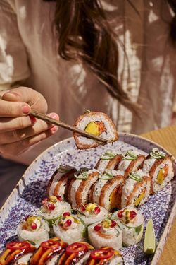 Assortiment de sushi frais présenté sur un grand plat, avec des makis décorés et servis avec une tranche de citron vert.