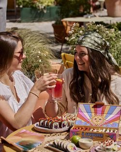Deux femmes dégustant des sushis à emporter et des boissons sur une terrasse ensoleillée de Côté Sushi Besançon.