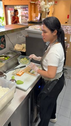 Préparation de sushi à emporter dans un restaurant japonais avec une employée assemblant des makis. Livraison disponible.
