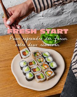 Sushi à emporter servi sur une assiette avec une main utilisant des baguettes en bois.