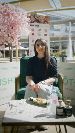 Client assis en terrasse chez Coté Sushi Tours avec plateau de sushis et décor de fleurs de cerisier en fond.