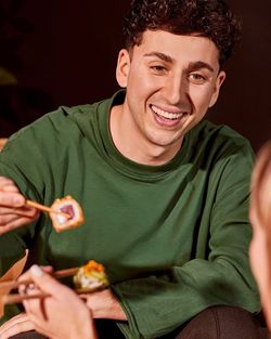 Client dégustant des sushis avec des baguettes dans un restaurant japonais, mettant en avant la livraison et à emporter.