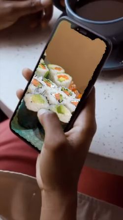 Commande de sushi à emporter affichée sur un smartphone, avec une tasse posée sur une table ronde claire