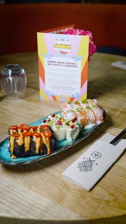 Sushi variés servis sur une assiette bleue posée sur une table en bois dans un restaurant japonais.