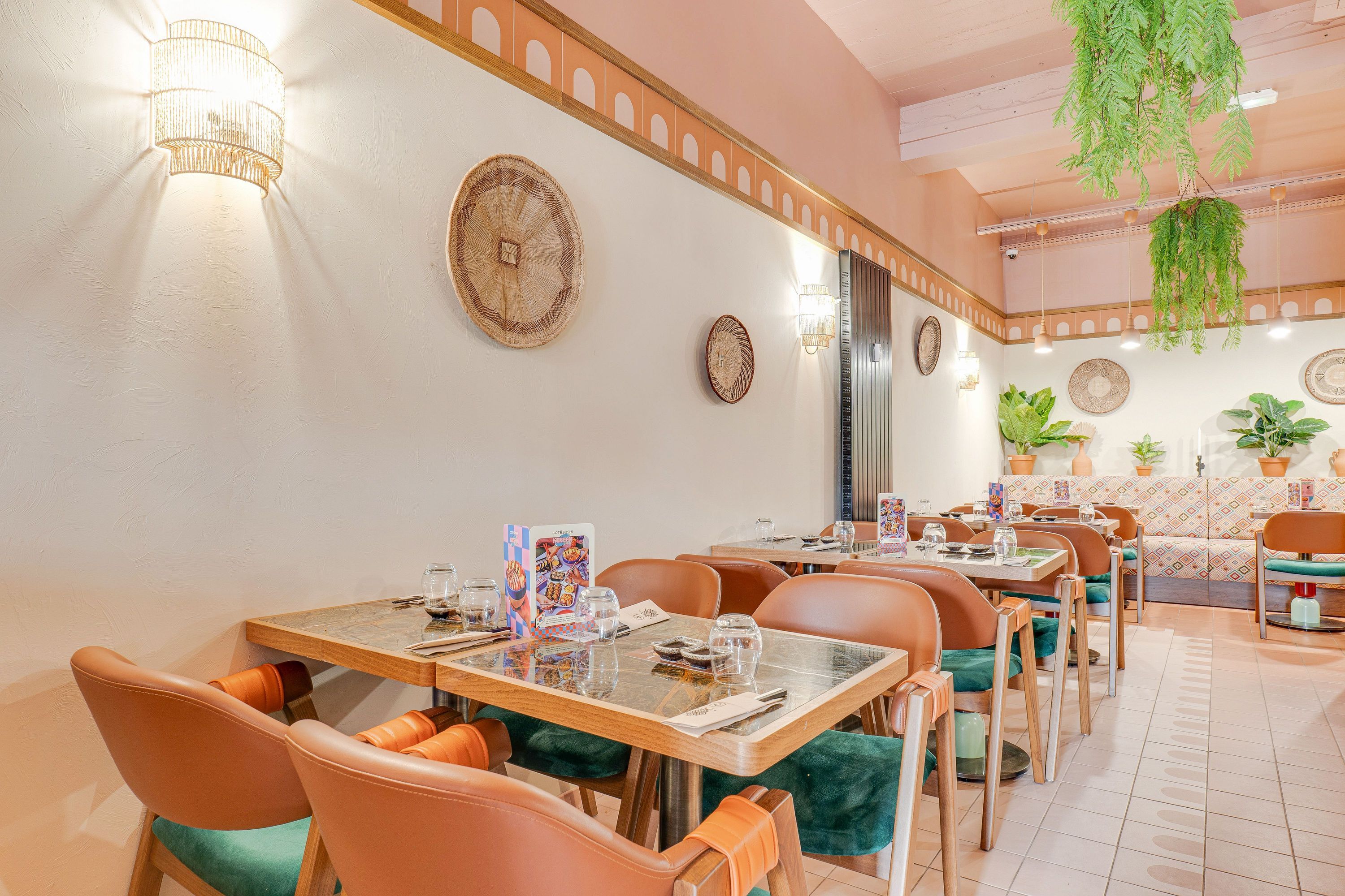 Salle lumineuse du restaurant japonais Côté Sushi avec tables en marbre, chaises cuir et décorations murales tissées.