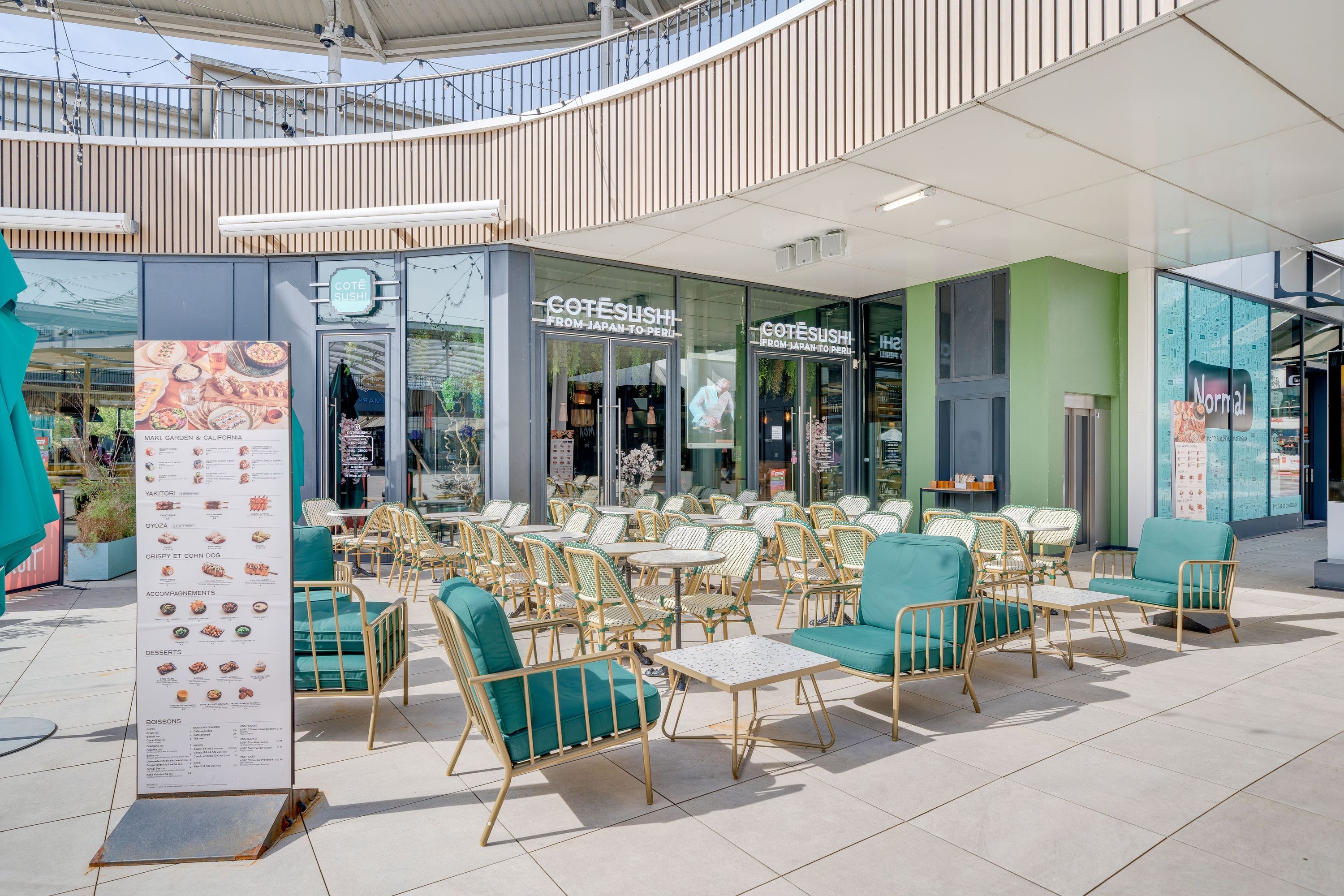 Terrasse extérieure avec tables et fauteuils verts devant le restaurant japonais Coté Sushi Tours