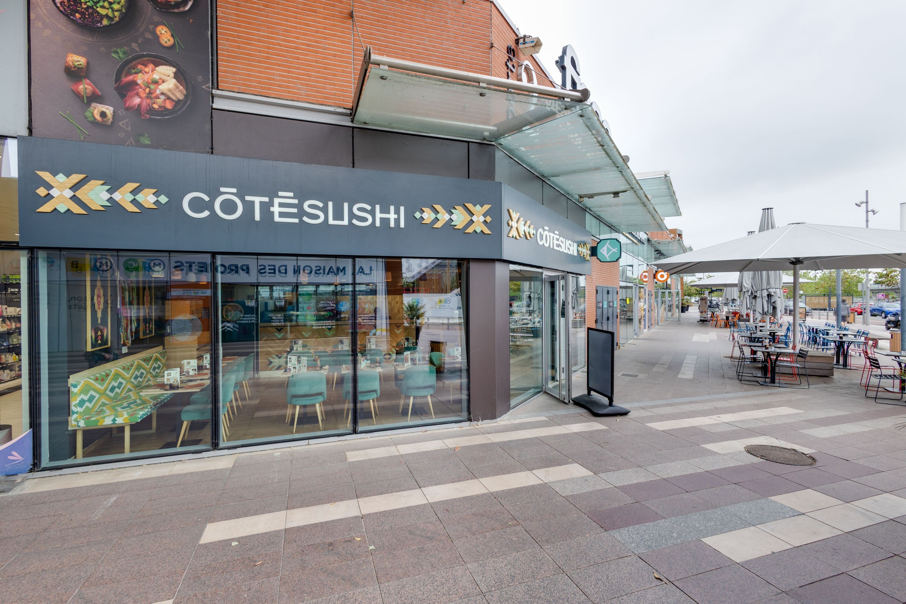 Façade du restaurant japonais Côté Sushi Labège avec terrasses extérieures et mobilier moderne en bois et métal.