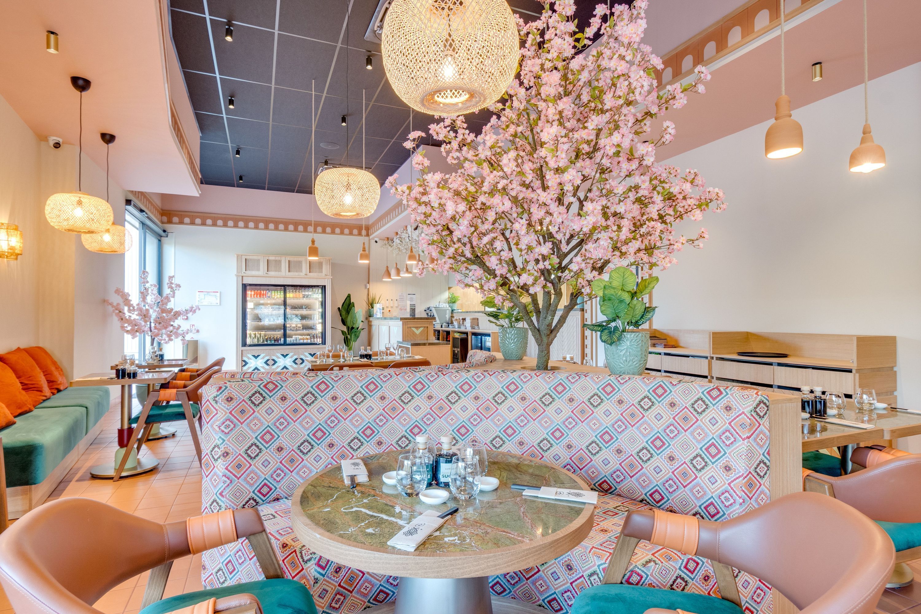 Intérieur lumineux d'un restaurant japonais avec tables rondes, chaises modernes et décorations florales.
