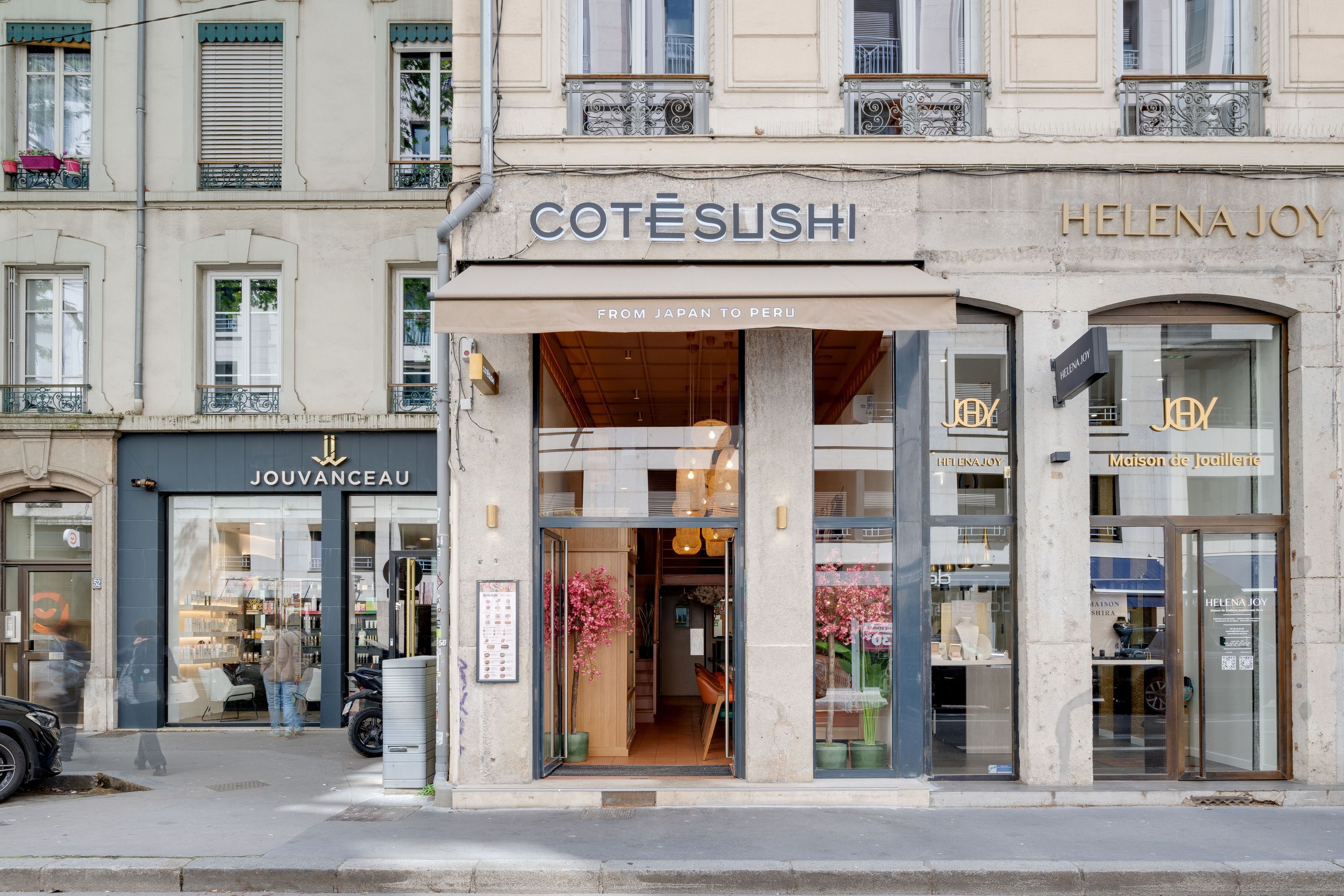 Façade du restaurant japonais Côté Sushi Lyon avec porte d'entrée en verre et enseigne claire sur rue urbaine.