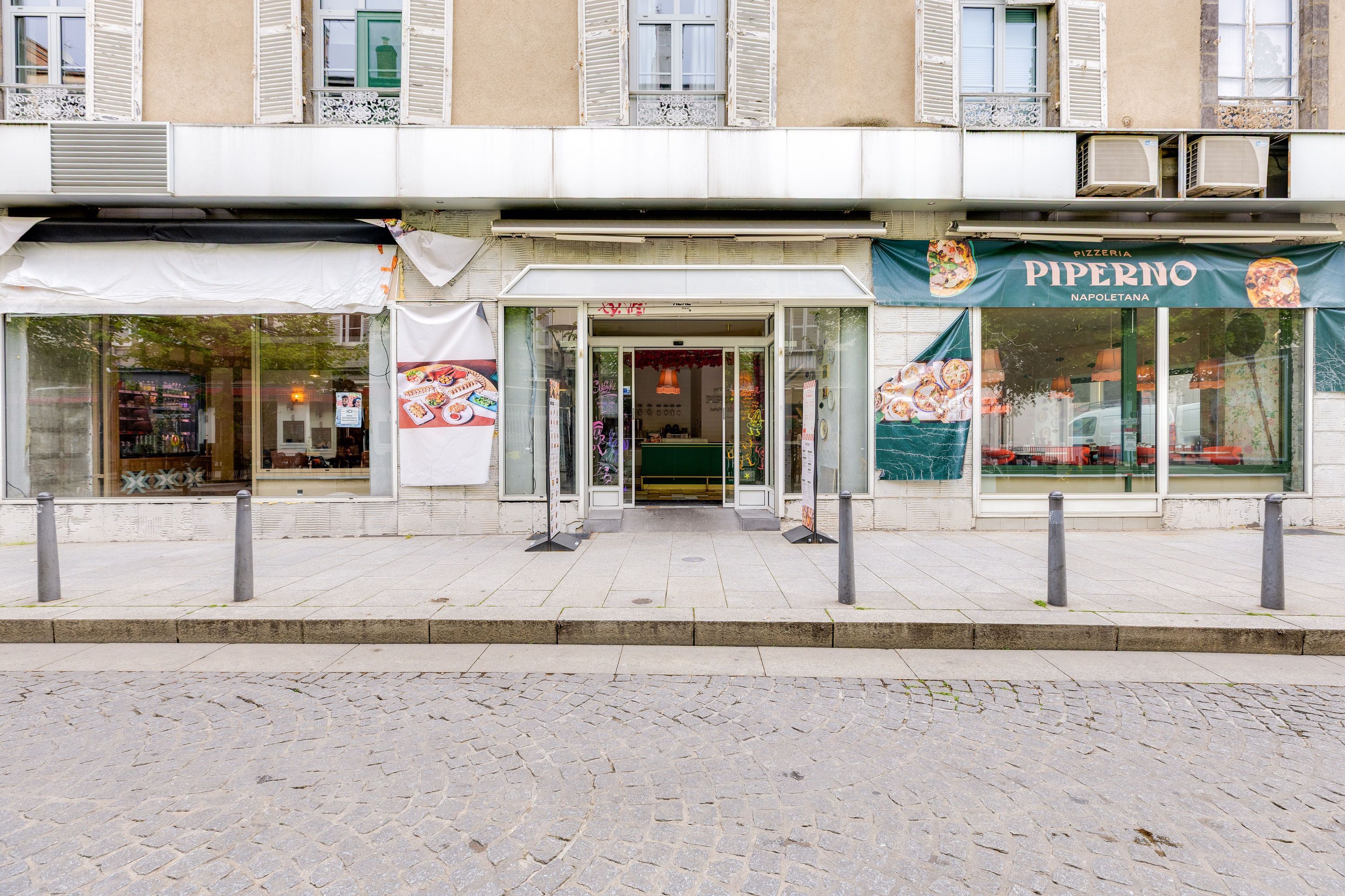Façade d'un restaurant japonais à emporter avec vitrines larges et entrée centrale donnant sur un trottoir pavé