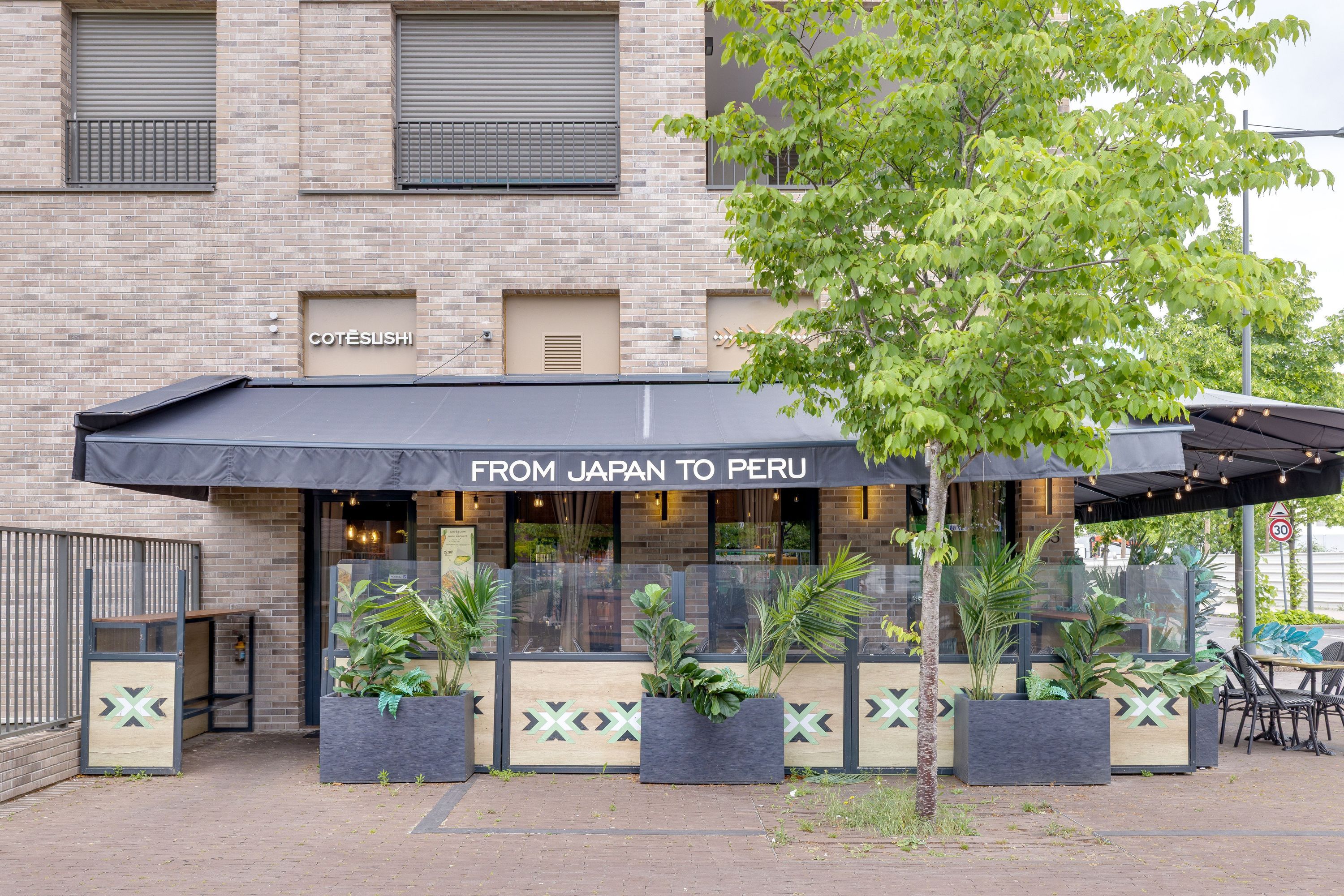 Terrasse extérieure avec plantes et mobilier sous auvent du restaurant japonais Côté Sushi à Asnières-sur-Seine.