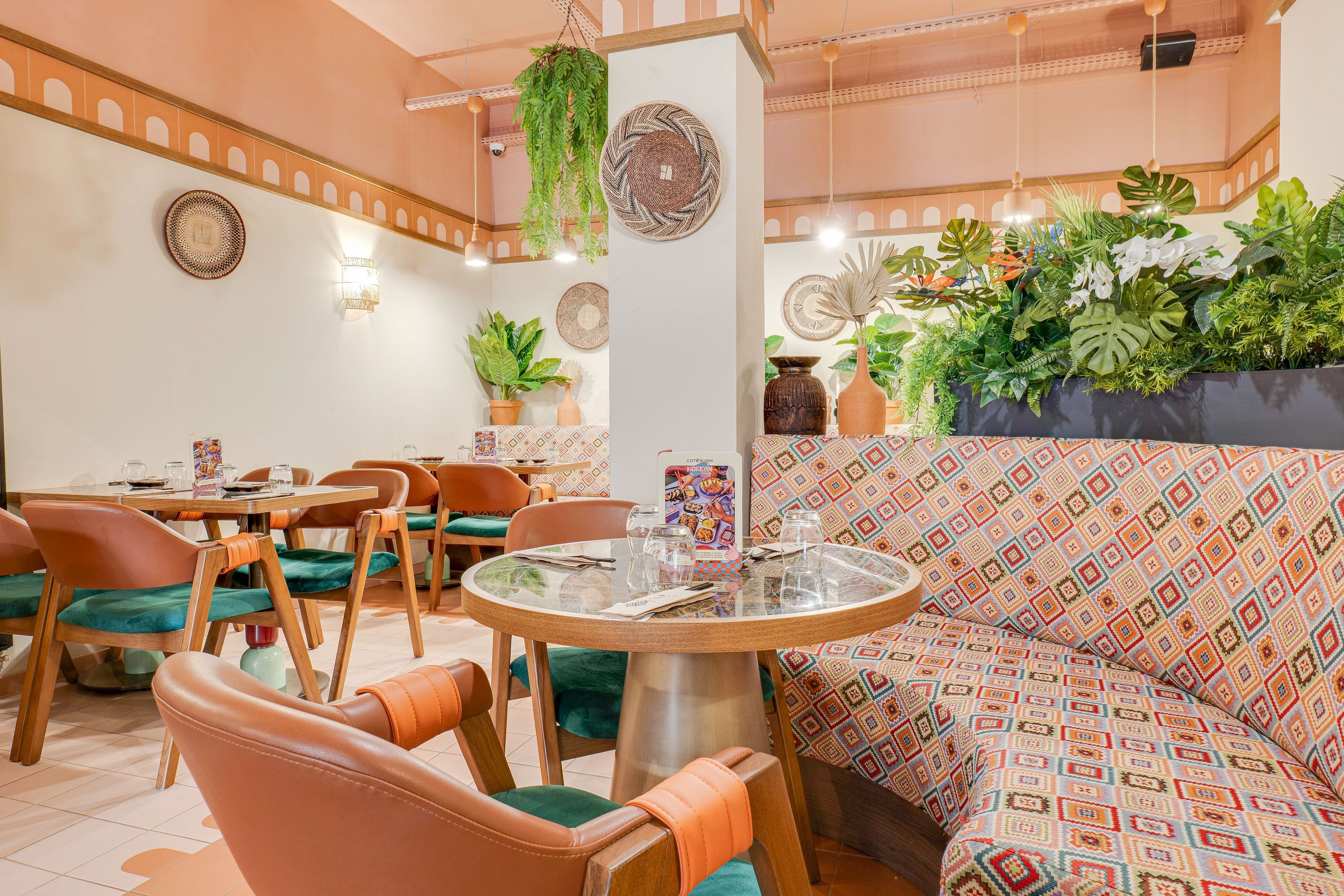 Salle paisible avec fauteuils en cuir, banquette à motifs géométriques et plantes dans restaurant japonais à emporter