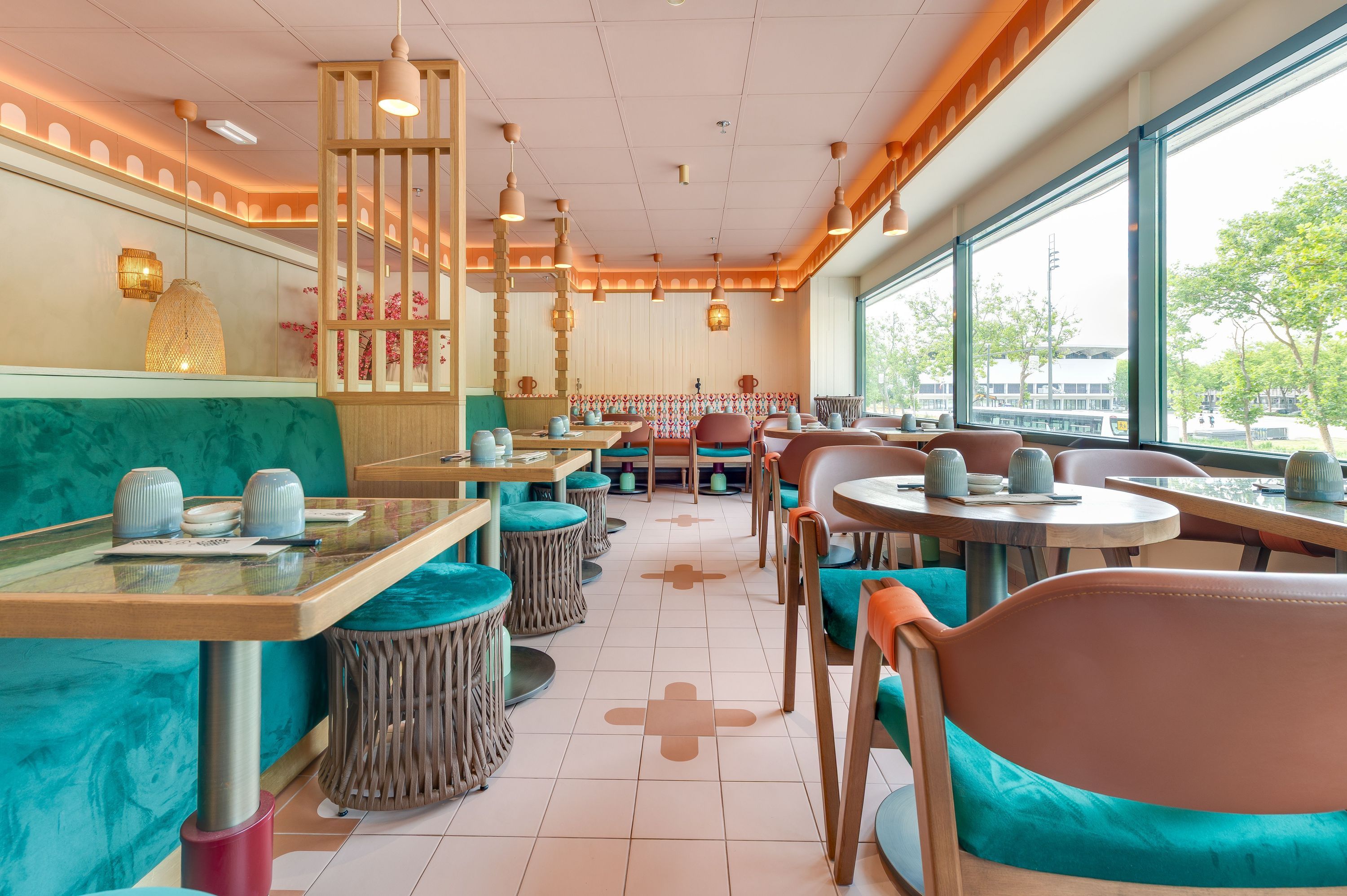 Intérieur d'un restaurant japonais avec tables, chaises colorées et grandes fenêtres sur l'extérieur.