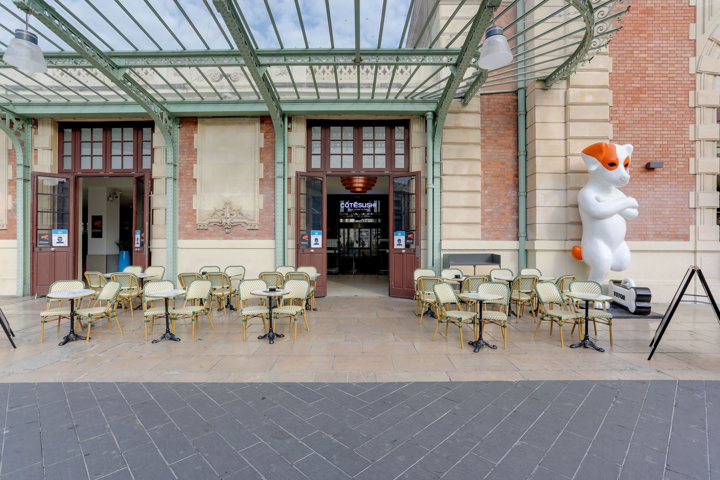 Terrasse extérieure avec tables et chaises devant le restaurant japonais Côté Sushi Gare de Nice, entrée sous une verrière.