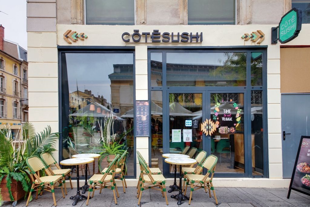 Façade du restaurant japonais Côté Sushi Nancy avec tables et chaises en terrasse en ville.