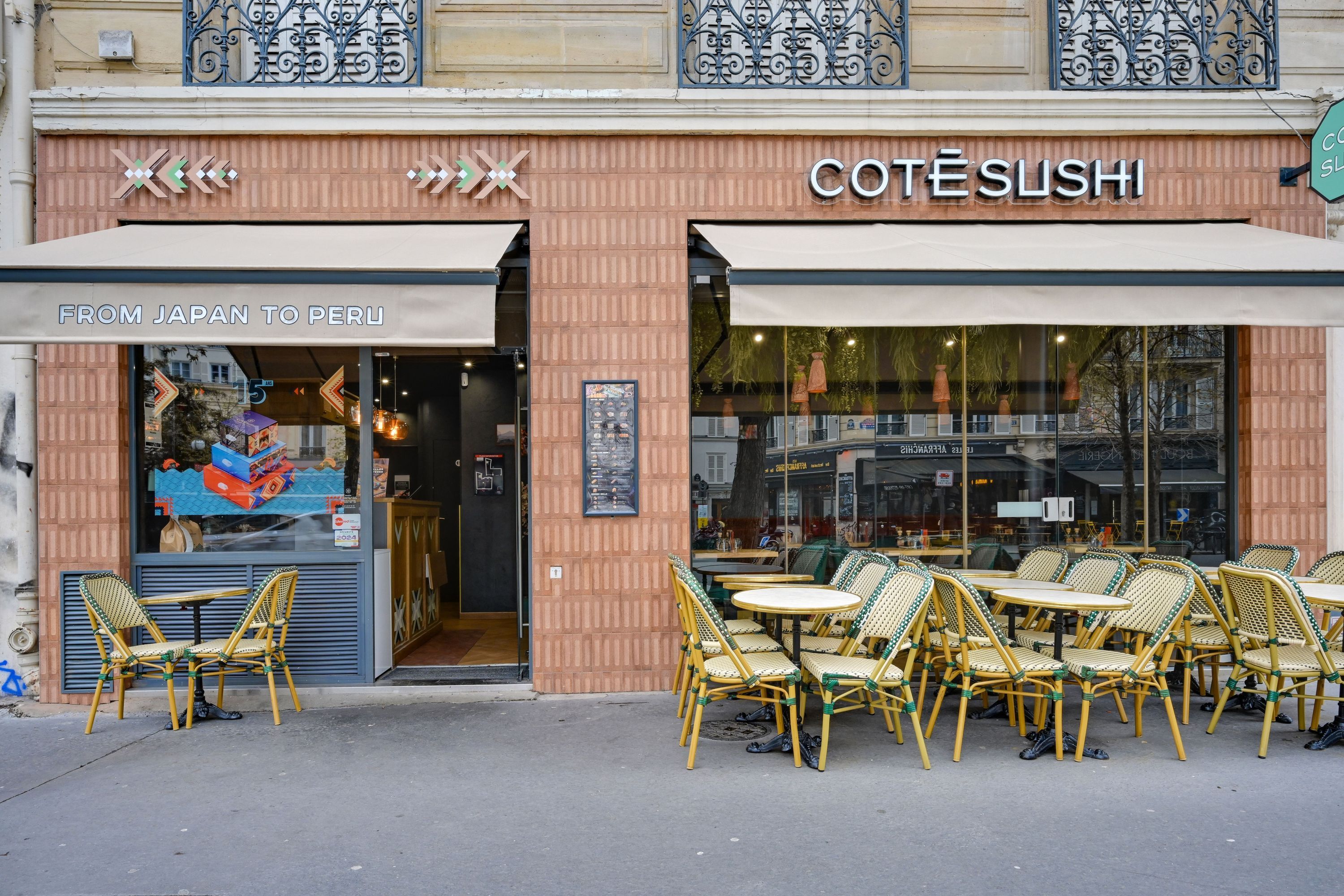 Façade du restaurant Côté Sushi Voltaire avec tables et chaises en terrasse pour sushi à emporter.