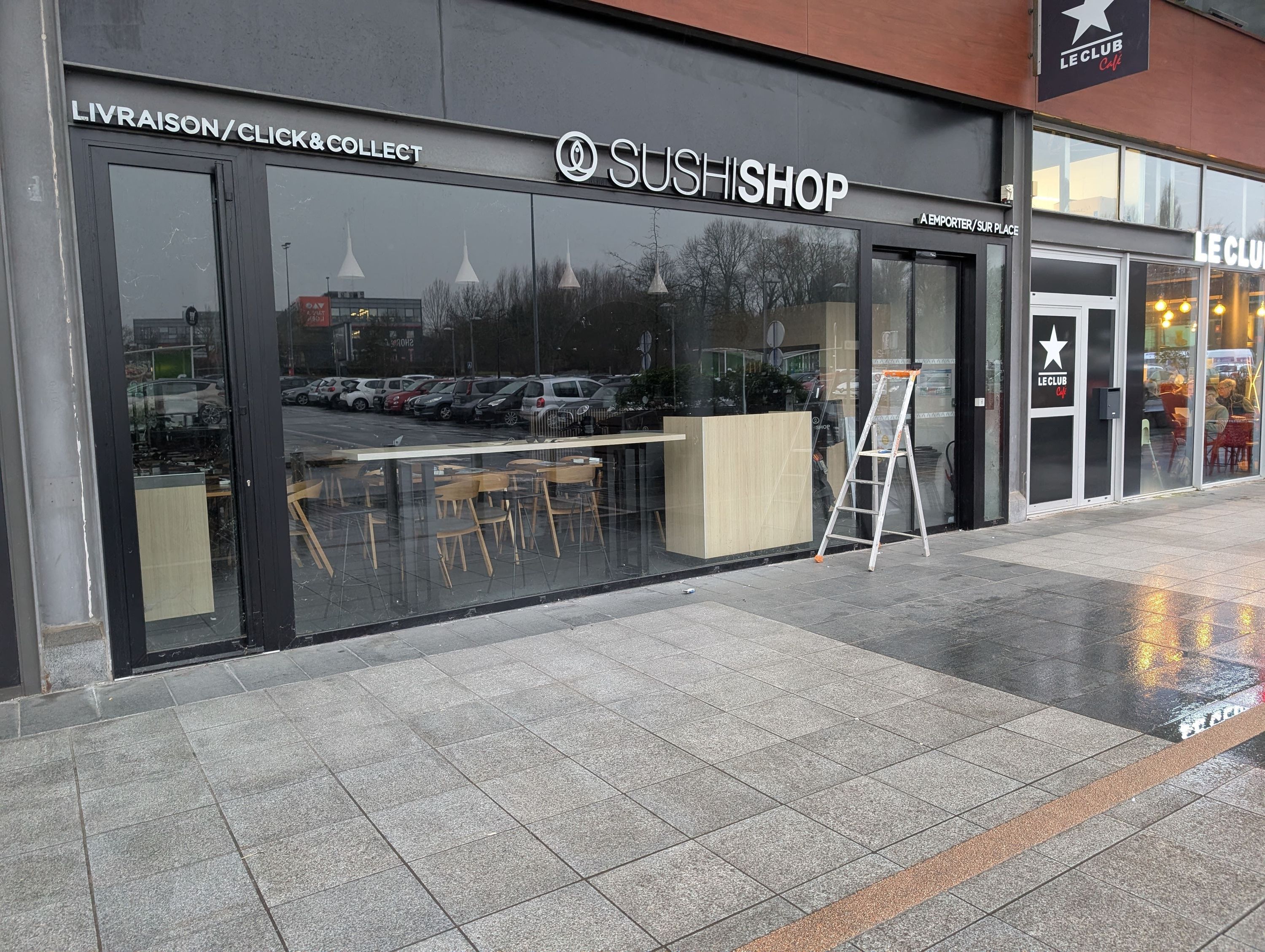 Façade d'un restaurant japonais avec vitrine en verre et logo Sushi Shop, proposant livraison et plats à emporter.