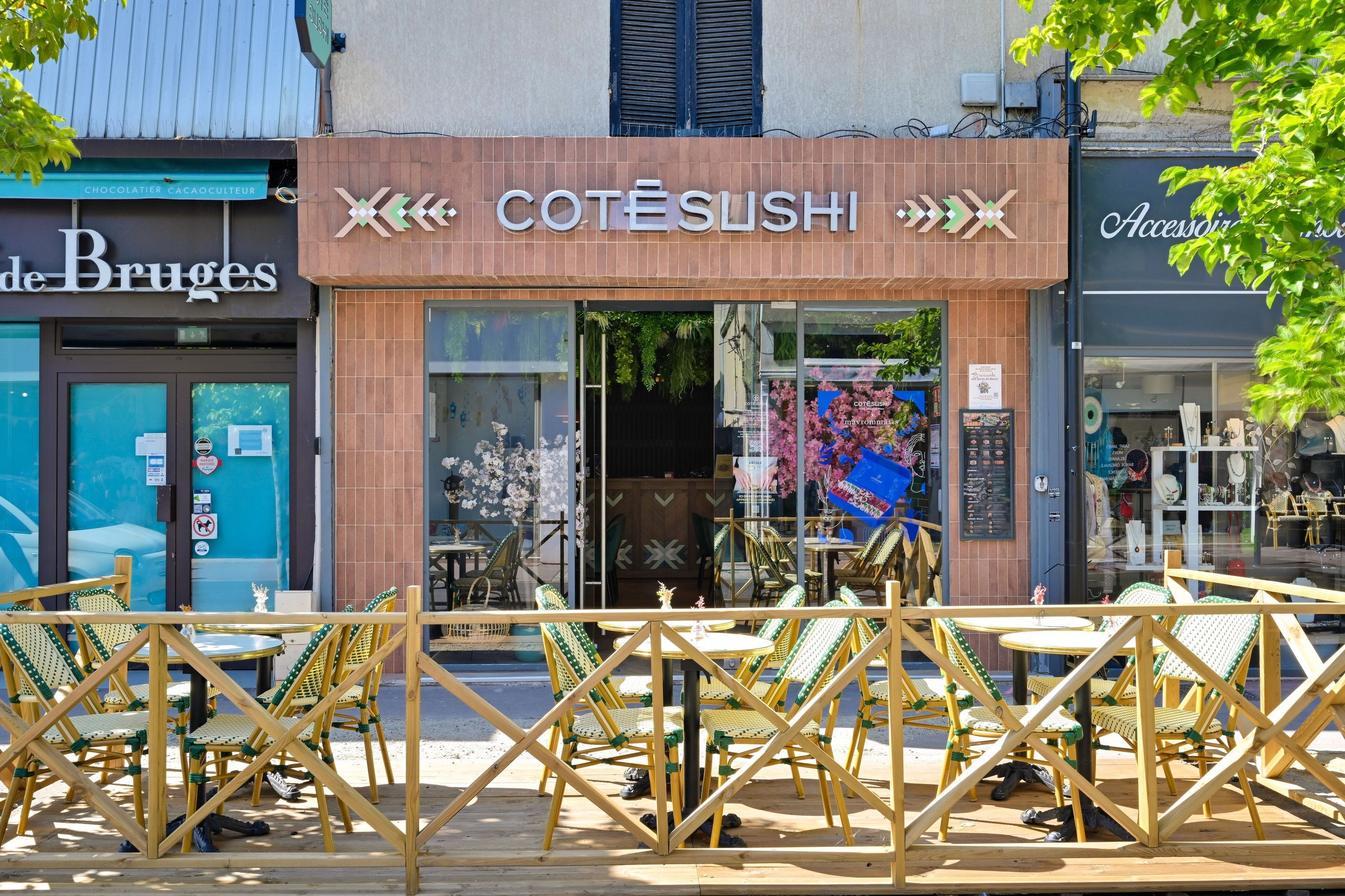 Façade du restaurant japonais Côté Sushi avec terrasse extérieure aménagée et chaises en rotin vert et beige.