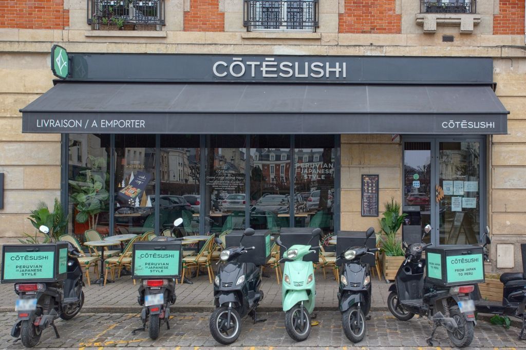 Façade du restaurant Côté Sushi Reims avec scooters de livraison alignés devant le restaurant japonais à emporter.