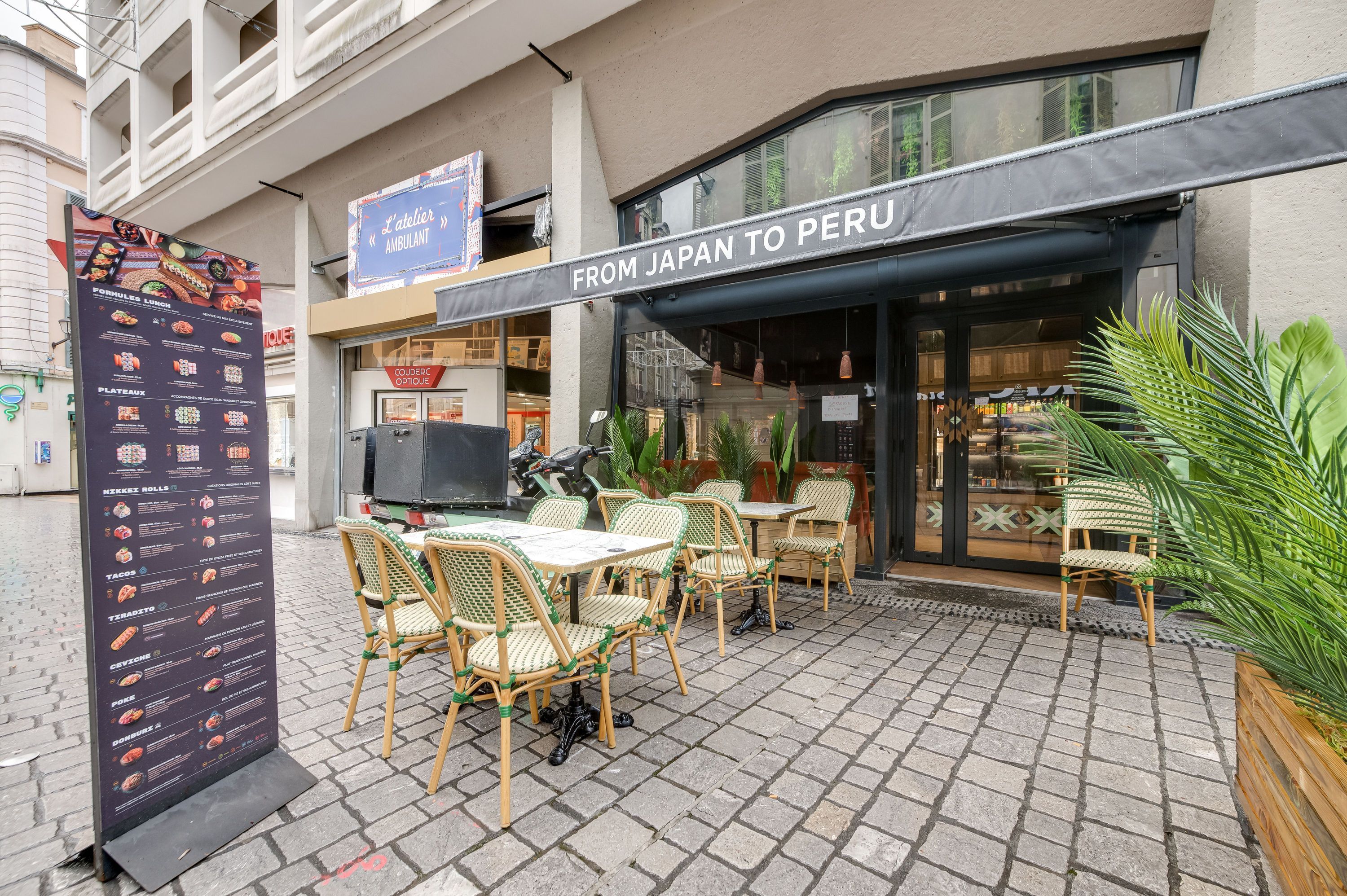Terrasse avec tables et chaises devant un restaurant japonais ouvert avec menu visible à l'extérieur en centre-ville.