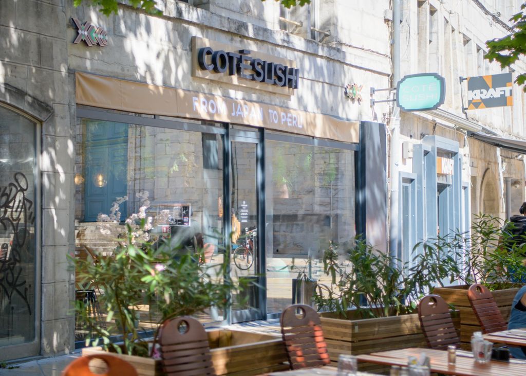 Façade de Côté Sushi Besançon, restaurant japonais avec terrasse extérieure et tables en bois.