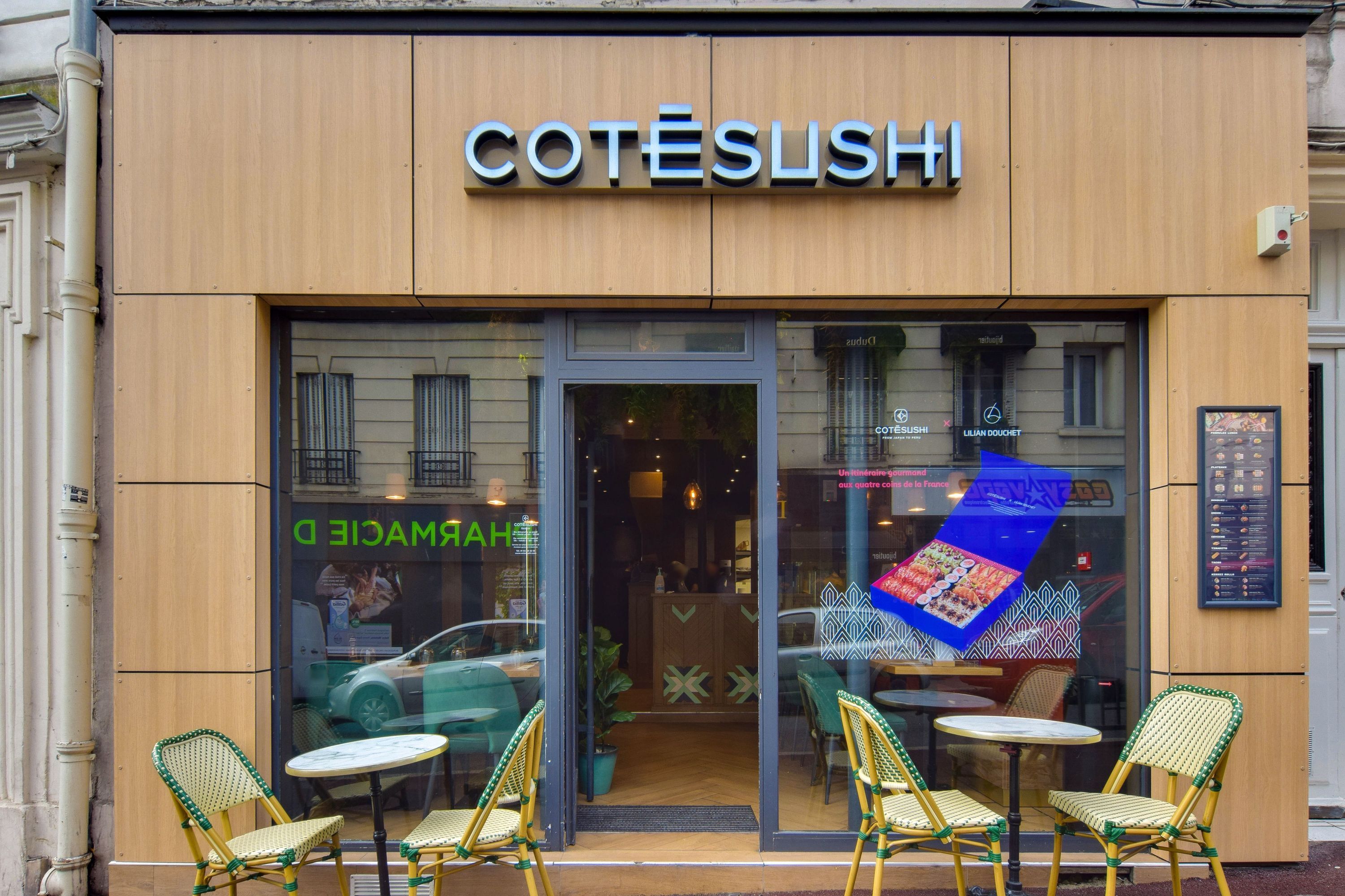 Façade du restaurant Côté Sushi Suresnes avec tables et chaises extérieures, menu visible à droite de la porte.