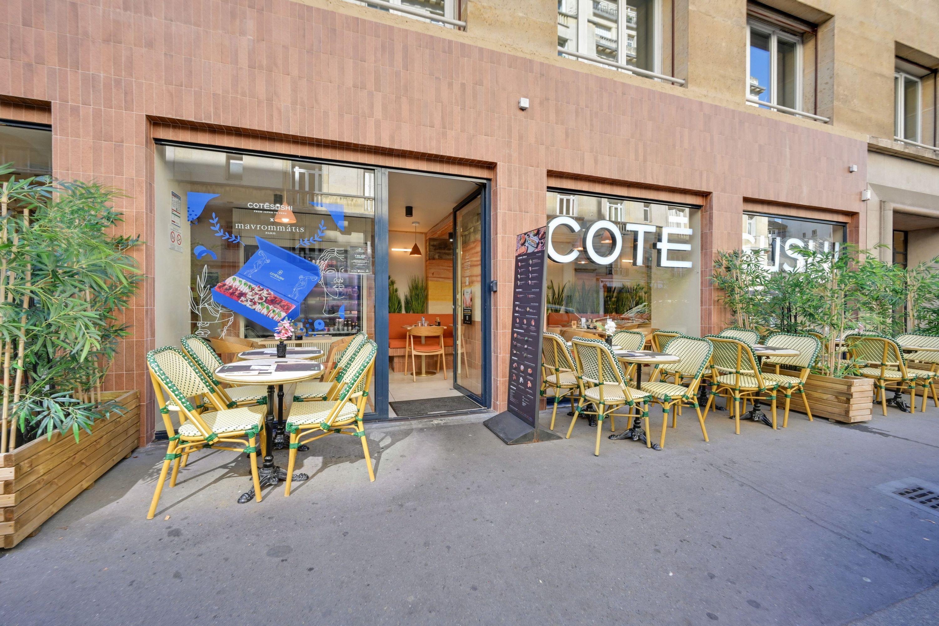Terrasse avec tables et chaises devant le restaurant japonais Côté Sushi Doumer, vitrine et menu visibles.