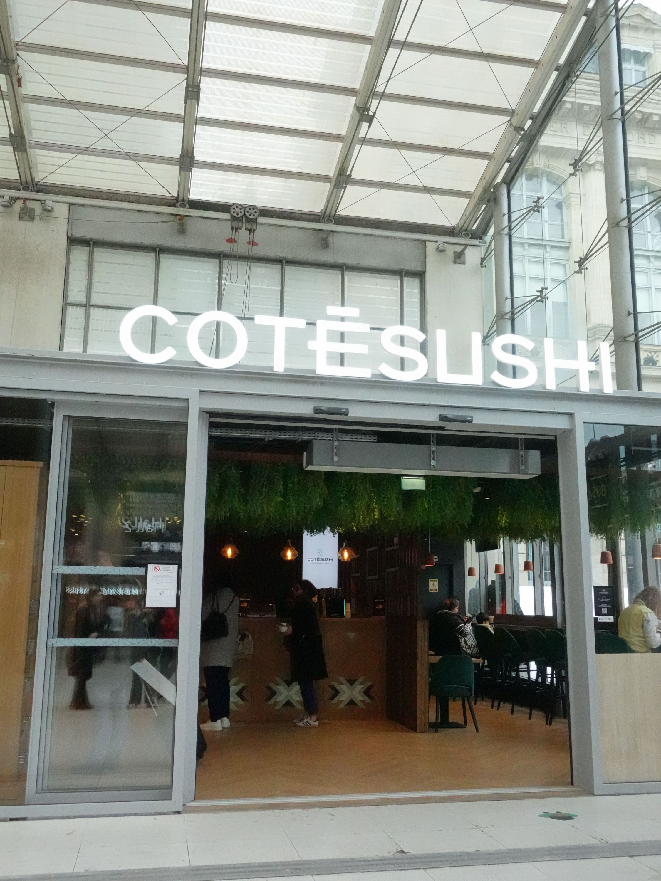 Façade moderne du restaurant Côté Sushi Gare du Nord avec grande enseigne lumineuse et intérieur visible par la vitrine