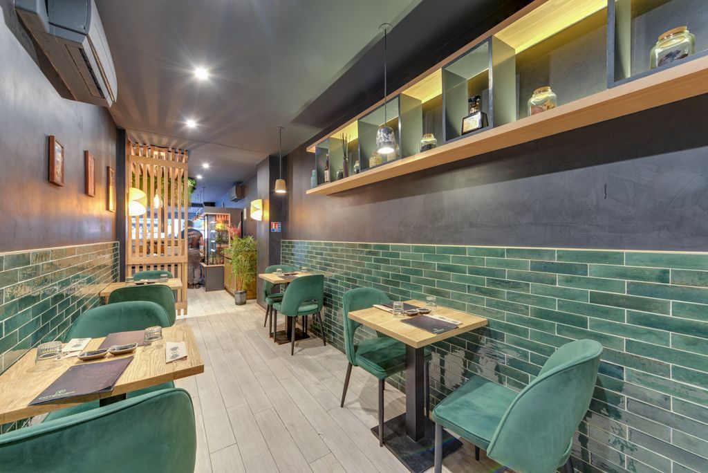 Intérieur du restaurant japonais Côté Sushi Boétie avec tables en bois, chaises vertes et décor moderne lumineux.