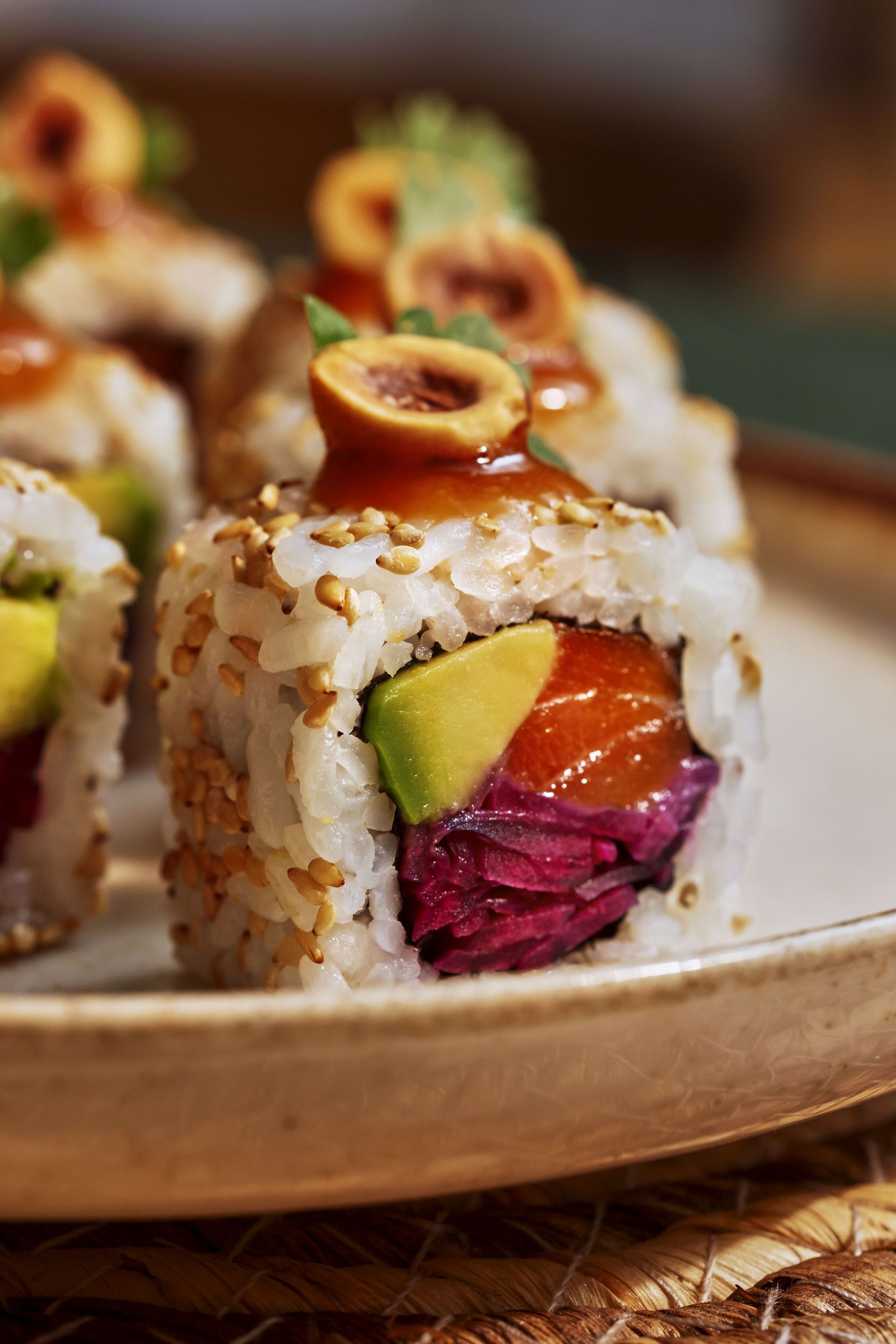 Petits rouleaux de sushi avec avocat, poisson cru et garniture croquante sur assiette claire.