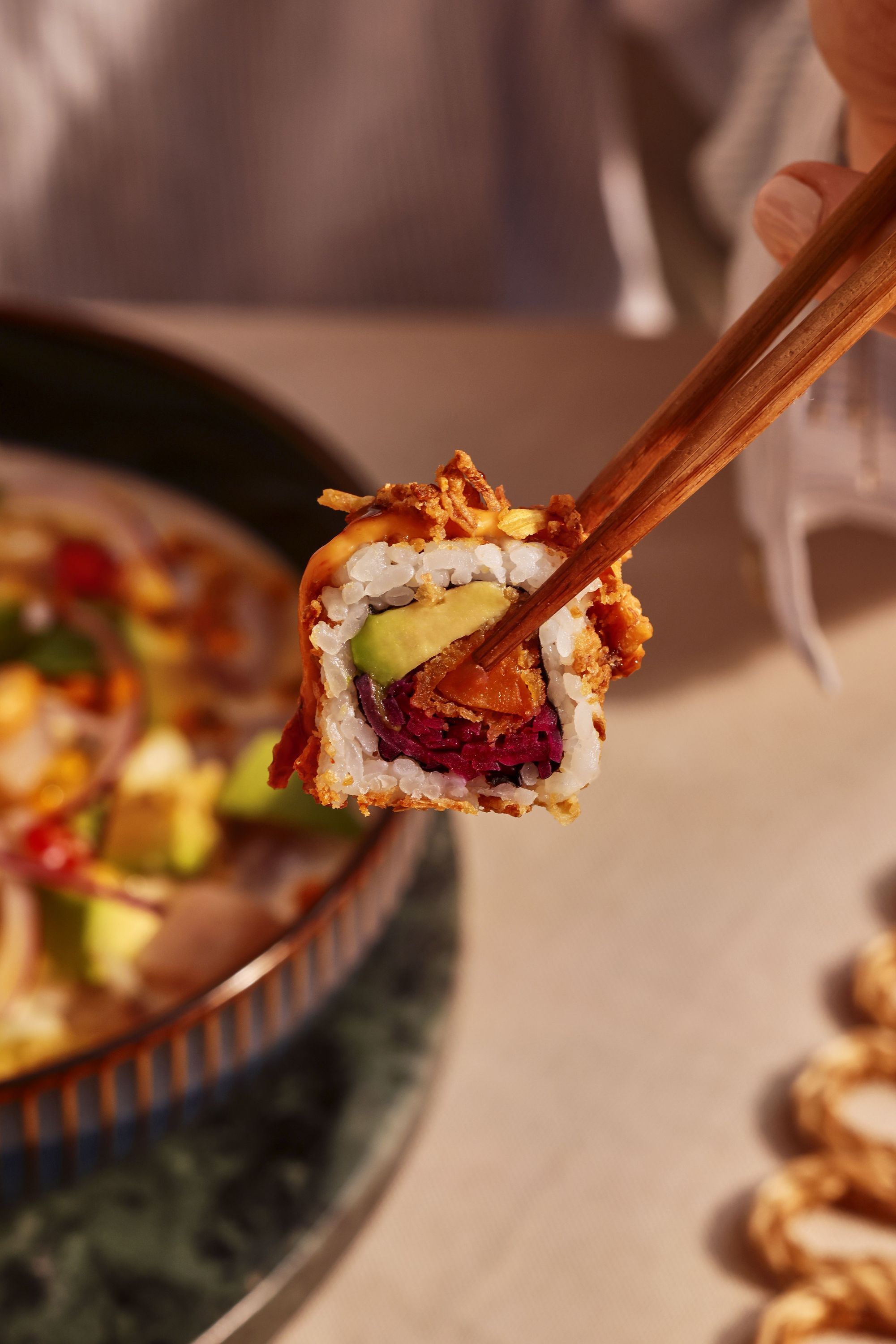 Sushi tenue avec des baguettes montrant des ingrédients frais au restaurant japonais Coté sushi Aix les Bains.