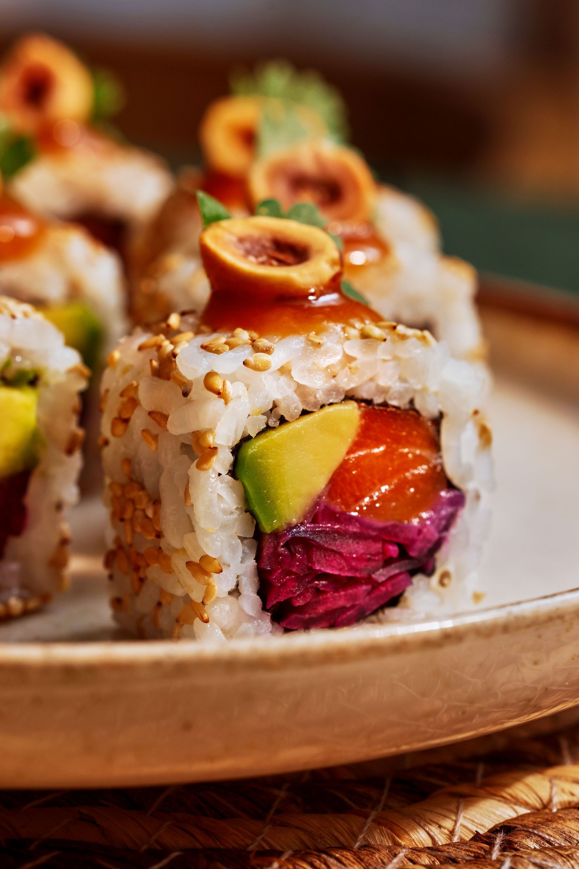 Sushi à emporter avec riz, avocat, poisson cru et garniture, présenté sur une assiette beige