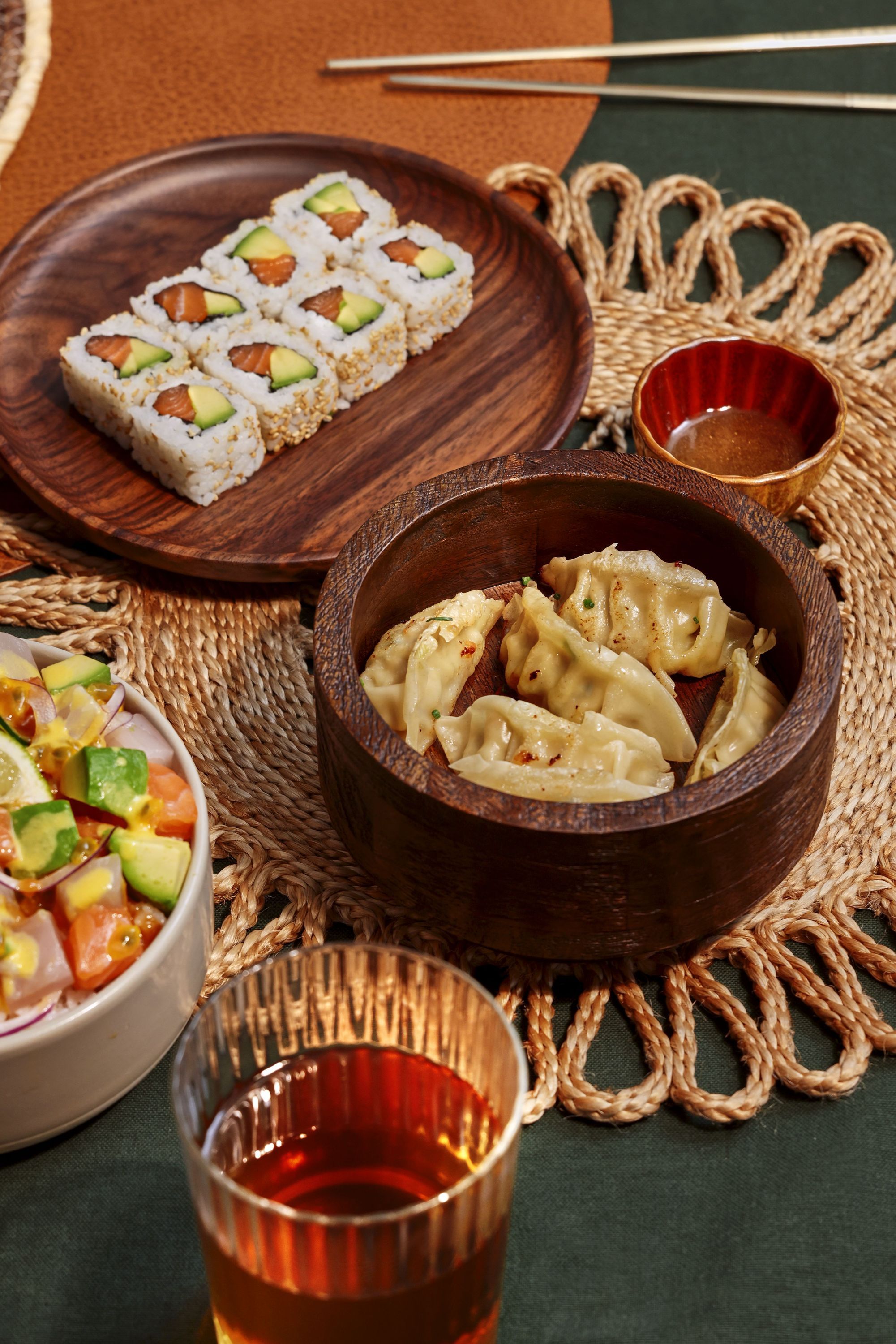 Assortiment de sushi et dumplings dans un restaurant japonais avec boisson et sauce soja à côté.